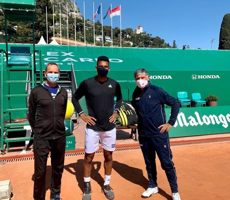 Felix stands with toni nadal on a clay court