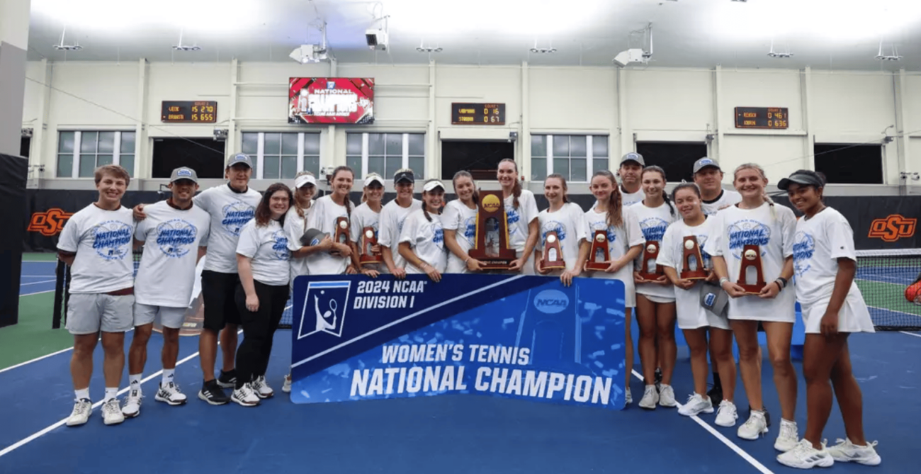 The Texas A&M women's tennis team pose with their trophy and a sign that reads "Women's tennis national champion"