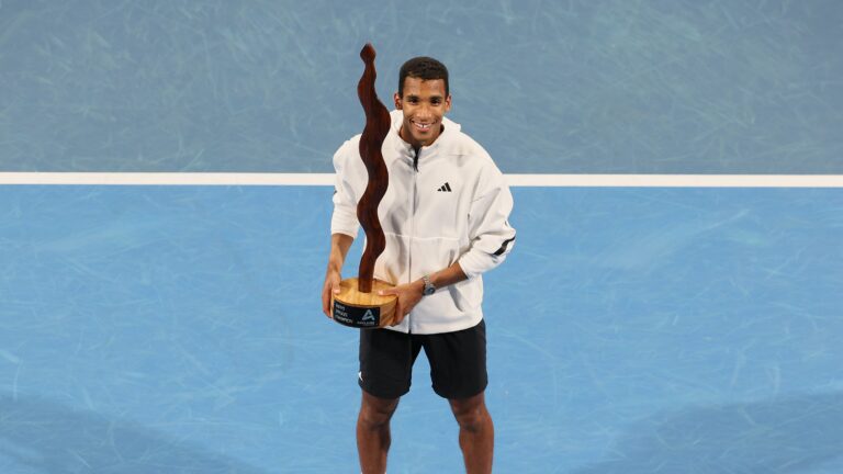 Felix Auger-Aliassime holds the trophy after winning the Adelaide International.