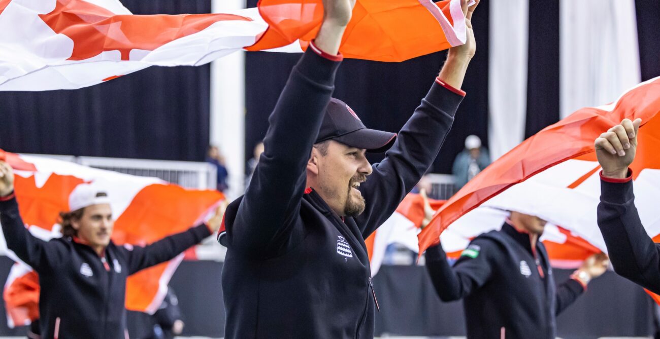 Frank Dancevic raises the Canadian flag above his head during after Canada's victory over Korea at the Davis Cup in Montreal in 2024.