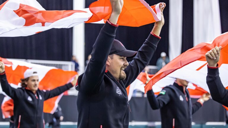 Frank Dancevic raises the Canadian flag above his head during after Canada's victory over Korea at the Davis Cup in Montreal in 2024.