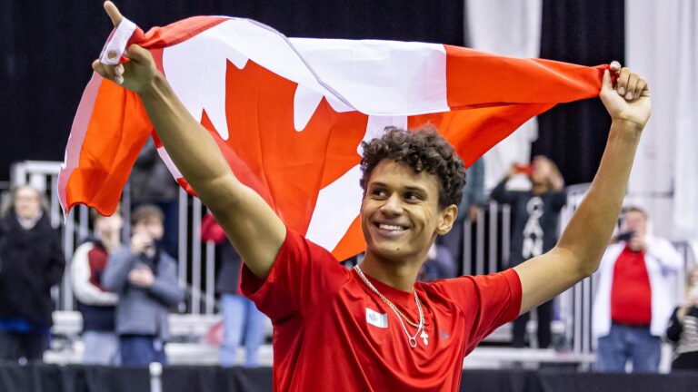 Gabriel Diallo holds a Canadian flag over his head during Canada's Davis Cup win in Montreal in 2024. Canada is hosting the qualifier again in 2025.