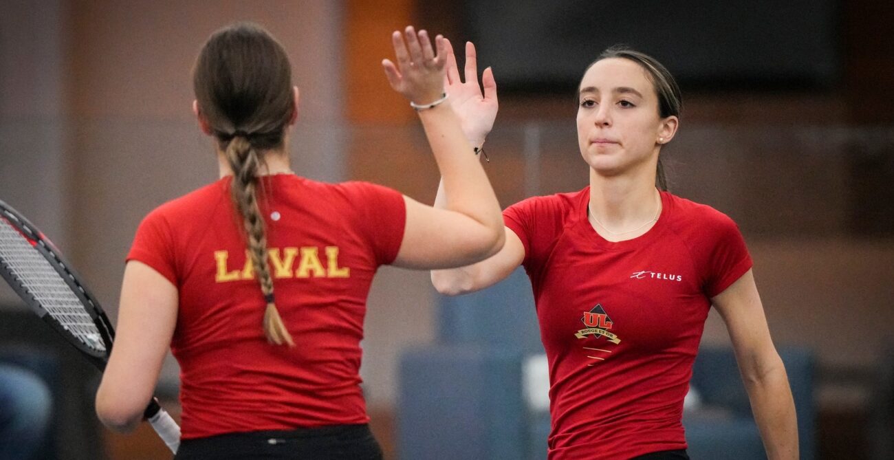 Two players for the Laval University Rouge et Or, one with back to camera and one facing, high-five.