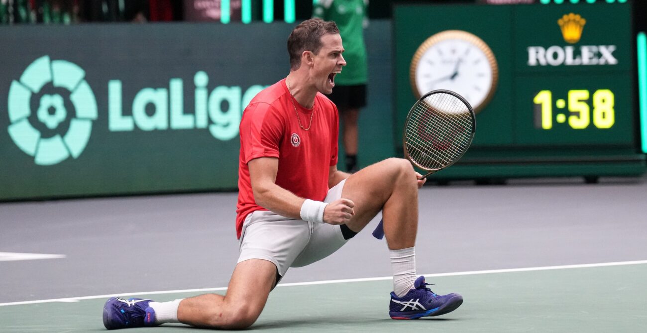 Vasek Pospisil kneels down, pumps his fist, and shouts during a win at the Davis Cup.