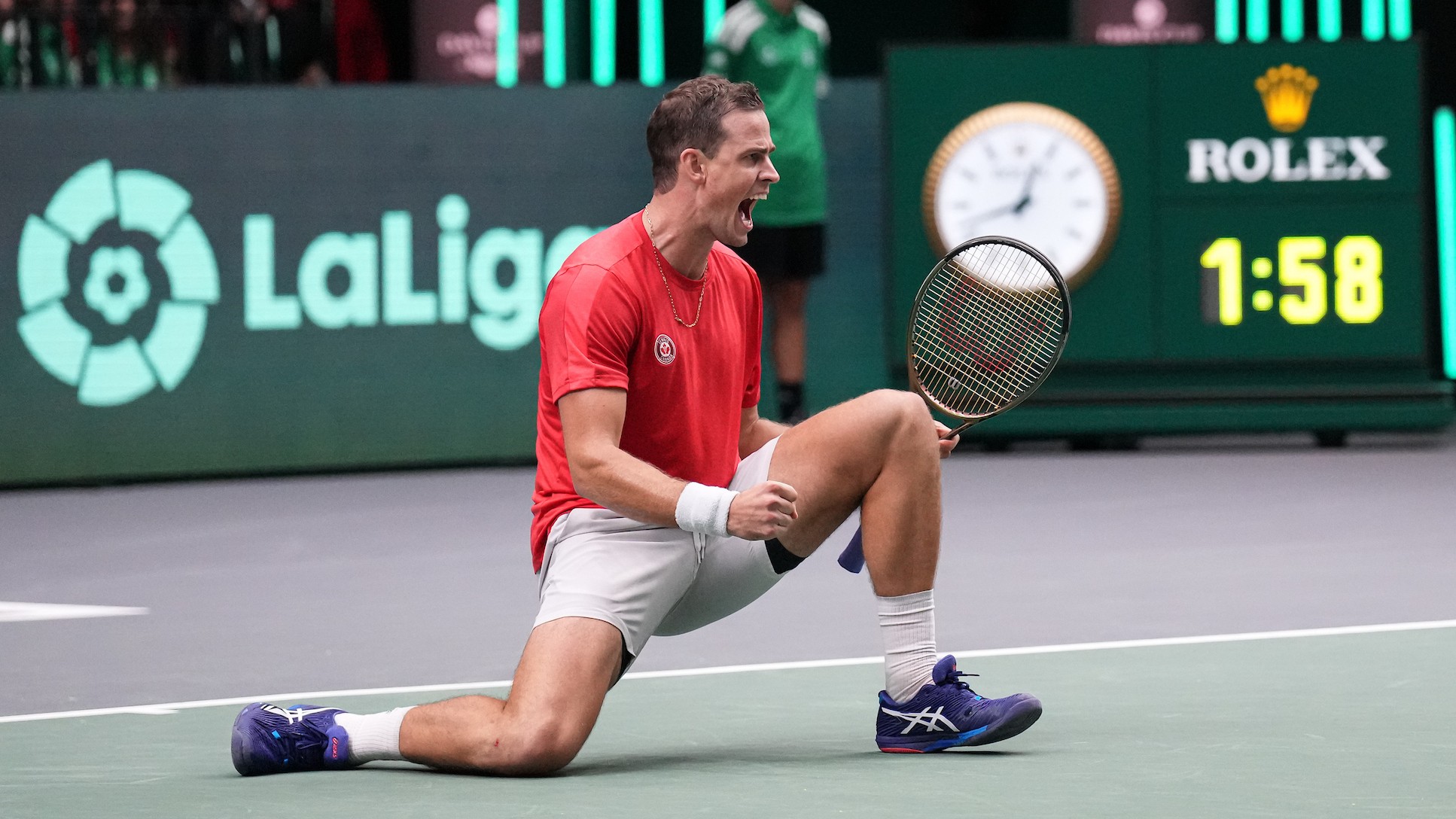 Vasek Pospisil kneels down, pumps his fist, and shouts during a win at the Davis Cup.