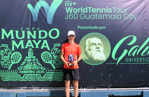 Canadian Joshua Adamson holds his trophy in front of a branded wall at the ITF junior event in Guatemala.